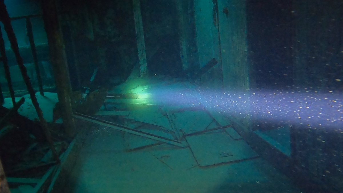 A light beam cutting through machinery inside a wreck's interior