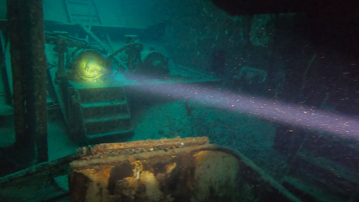 A light beam illuminating machinery inside a wreck's interior